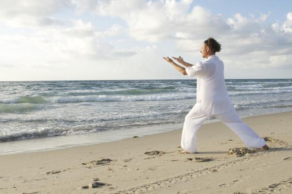 Homme pratiquant le Tai-Chi sur la plage